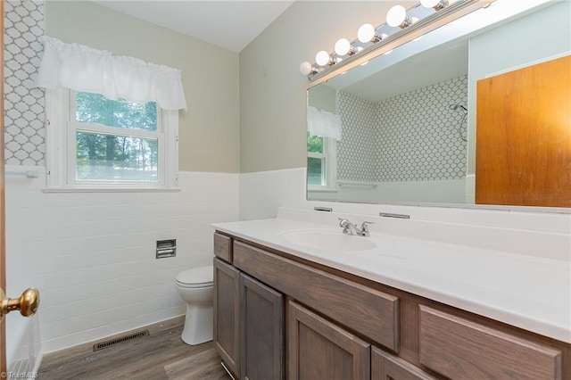 bathroom featuring tile walls, vanity, wood-type flooring, and toilet