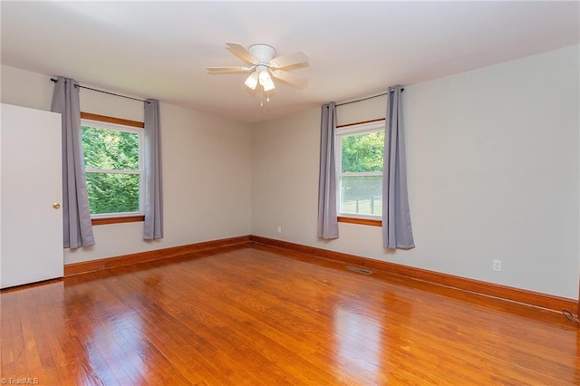 unfurnished room with hardwood / wood-style floors, a healthy amount of sunlight, and ceiling fan