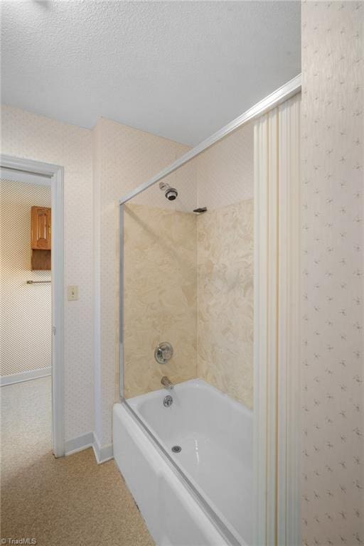 bathroom featuring a textured ceiling and tiled shower / bath