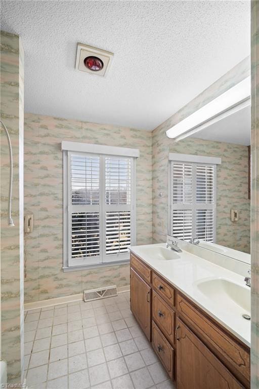 bathroom with tile patterned floors, vanity, a shower with shower door, and a textured ceiling