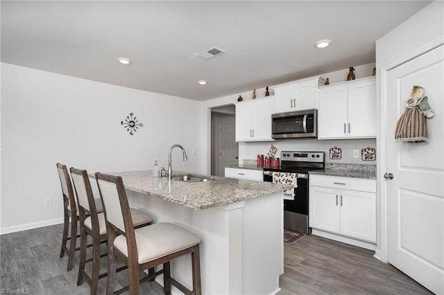4997 Payne St, Trinity, NC 27370 - kitchen featuring appliances with stainless steel finishes, a sink, a center island with sink, white cabinets, and a kitchen breakfast bar