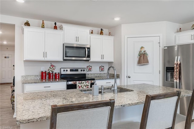 4997 Payne St, Trinity, NC 27370 - kitchen featuring stainless steel appliances, a sink, white cabinets, a breakfast bar, and a kitchen island with sink