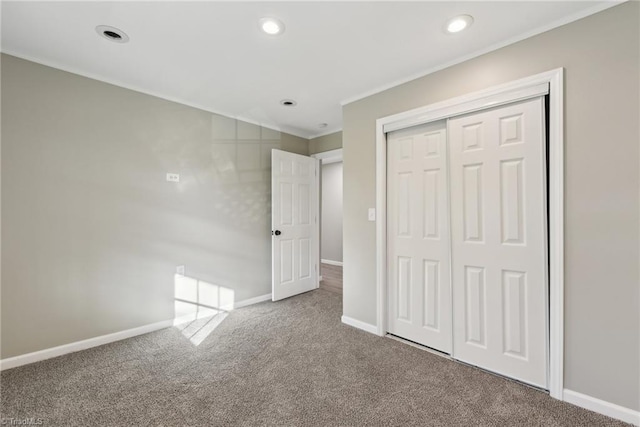 unfurnished bedroom with crown molding, carpet flooring, and a closet