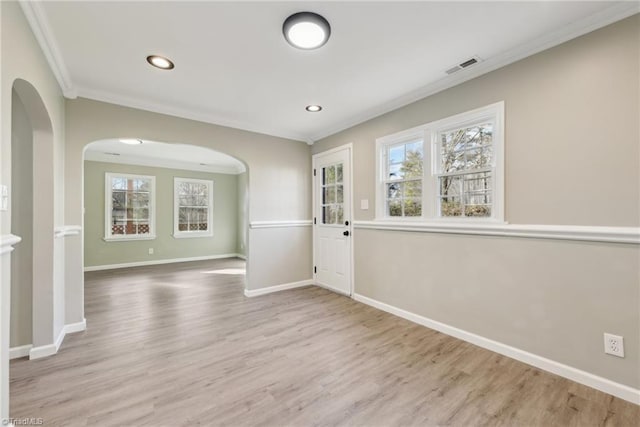 empty room featuring crown molding, plenty of natural light, and light hardwood / wood-style flooring