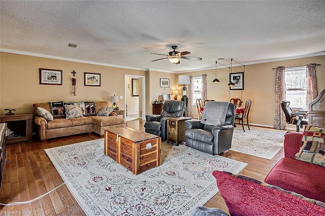 living area with a textured ceiling, ornamental molding, dark wood finished floors, and a ceiling fan