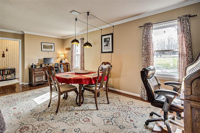 dining space with a textured ceiling, ornamental molding, wood finished floors, and baseboards