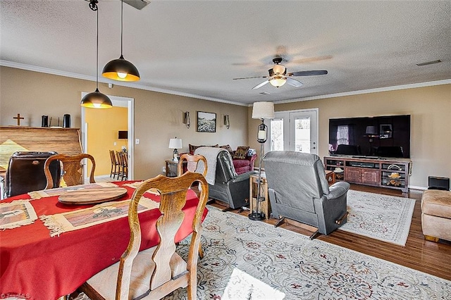 dining room with baseboards, a ceiling fan, wood finished floors, crown molding, and a textured ceiling