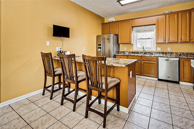 kitchen featuring brown cabinets, a kitchen bar, stainless steel appliances, and a peninsula