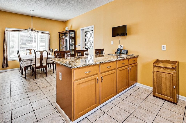 kitchen featuring a peninsula, light stone countertops, hanging light fixtures, a textured ceiling, and light tile patterned flooring