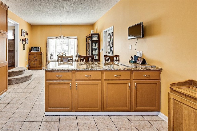 kitchen featuring a textured ceiling, light stone counters, and light tile patterned flooring