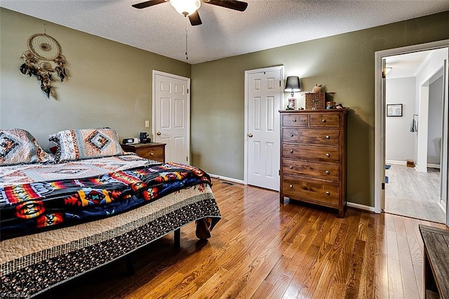 bedroom featuring wood-type flooring, baseboards, ceiling fan, and a textured ceiling