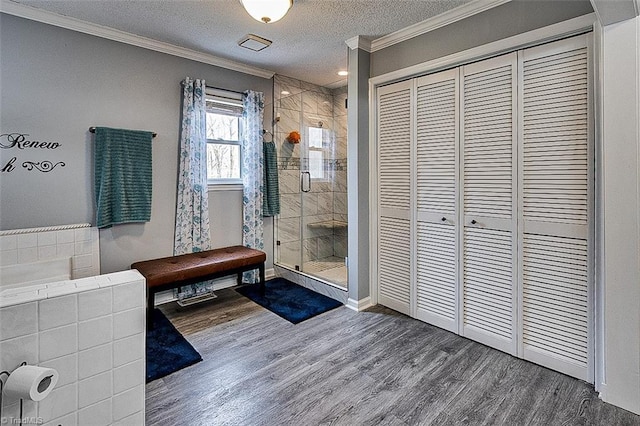 full bathroom with a textured ceiling, wood finished floors, ornamental molding, a closet, and a stall shower