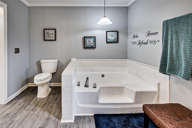 full bathroom featuring a garden tub, toilet, wood finished floors, baseboards, and crown molding