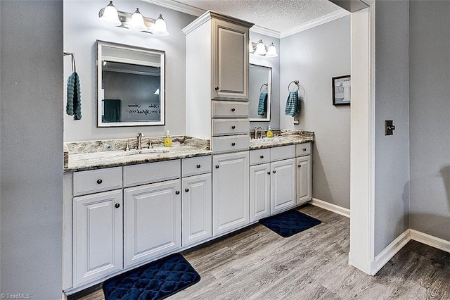 bathroom featuring crown molding, a sink, a textured ceiling, and wood finished floors