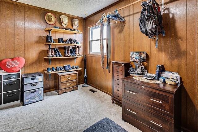 home office featuring a textured ceiling, wooden walls, visible vents, and carpet flooring