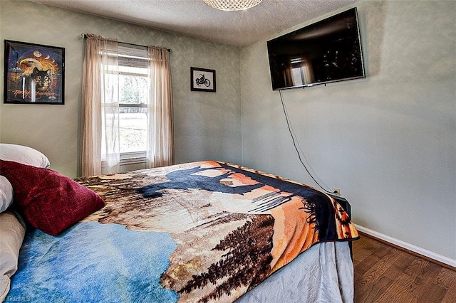 bedroom featuring a textured ceiling, wood finished floors, and baseboards