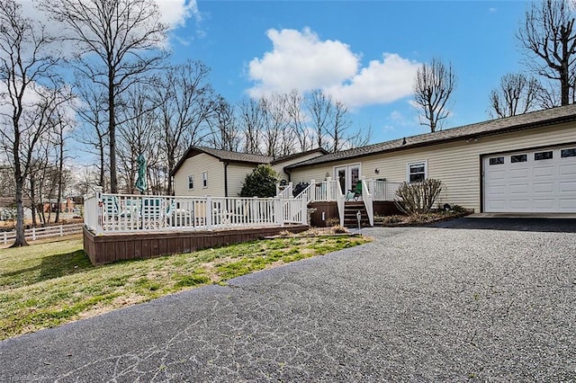 view of front of home featuring a garage, driveway, a wooden deck, and fence