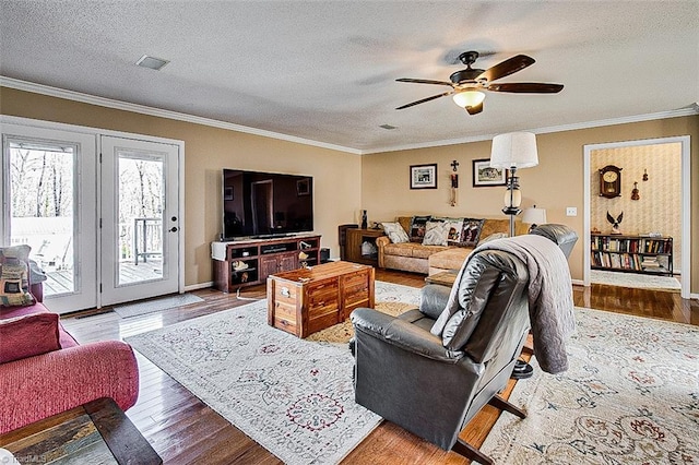 living area featuring baseboards, visible vents, ornamental molding, wood finished floors, and a textured ceiling