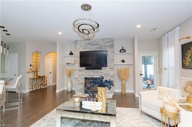 living room featuring built in shelves, a fireplace, and dark wood-type flooring