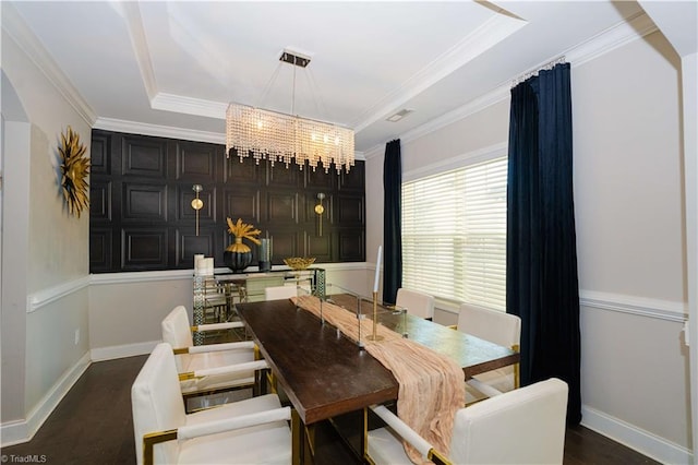 dining room featuring an inviting chandelier, dark hardwood / wood-style floors, a raised ceiling, and ornamental molding