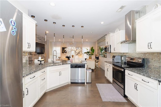 kitchen featuring pendant lighting, sink, decorative backsplash, appliances with stainless steel finishes, and kitchen peninsula