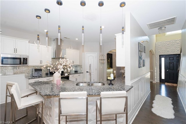 kitchen with white cabinets, a kitchen breakfast bar, sink, and hanging light fixtures