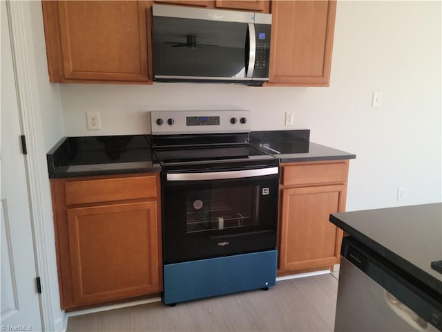 kitchen featuring light wood-type flooring, ceiling fan, and appliances with stainless steel finishes