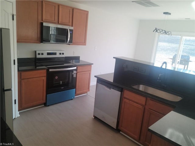 kitchen featuring pendant lighting, sink, light wood-type flooring, and appliances with stainless steel finishes