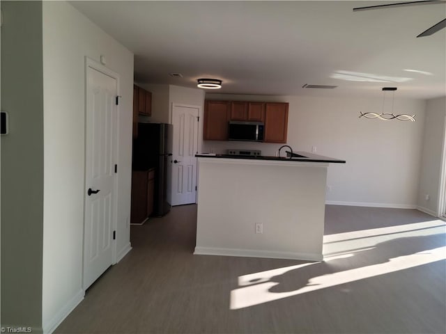 kitchen featuring black refrigerator, hanging light fixtures, sink, and light wood-type flooring