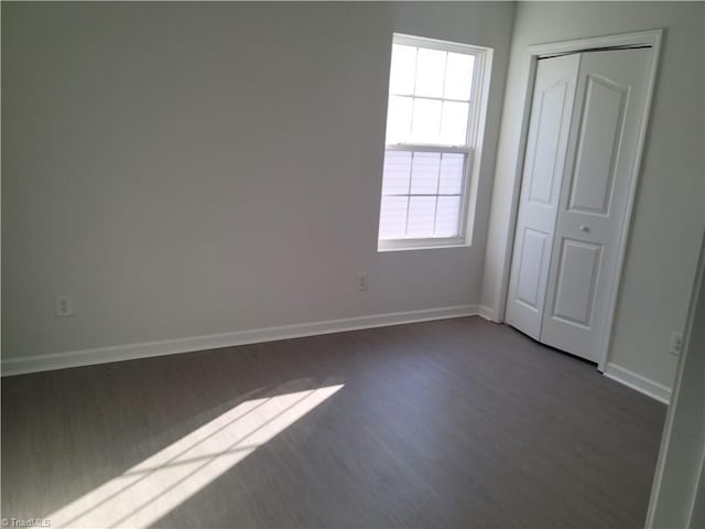 unfurnished bedroom with dark hardwood / wood-style flooring and a closet