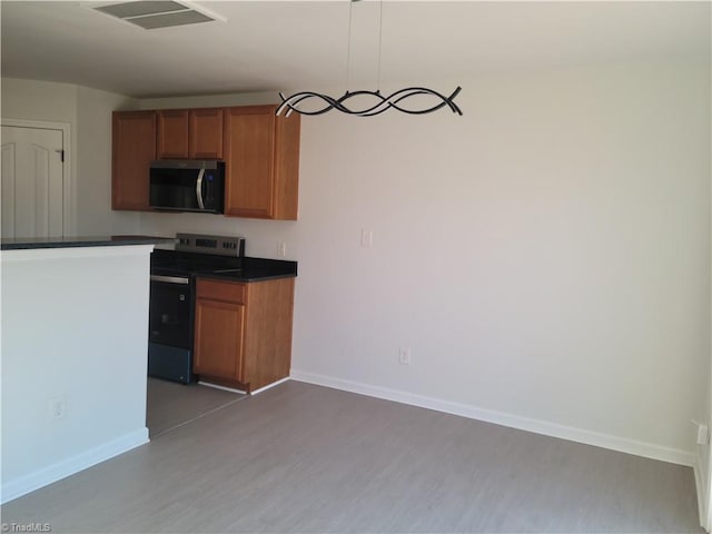 kitchen with decorative light fixtures, wood-type flooring, and stainless steel appliances