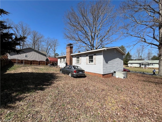 back of house with fence, a lawn, and a chimney