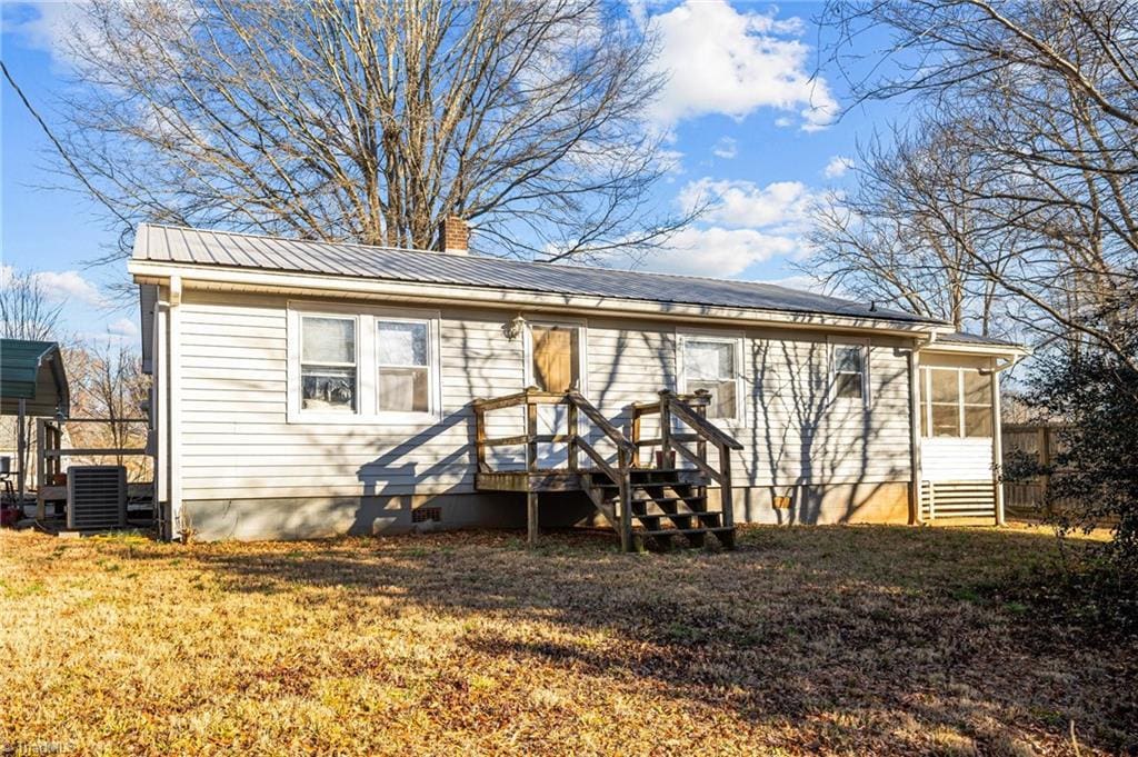 rear view of property with a sunroom and a lawn