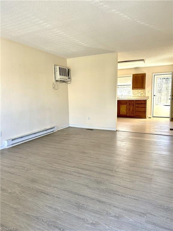 unfurnished room featuring baseboard heating, a wall mounted air conditioner, and wood finished floors