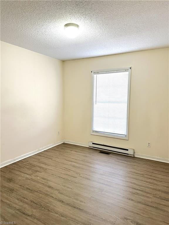 unfurnished room with baseboard heating, a textured ceiling, and dark wood-type flooring