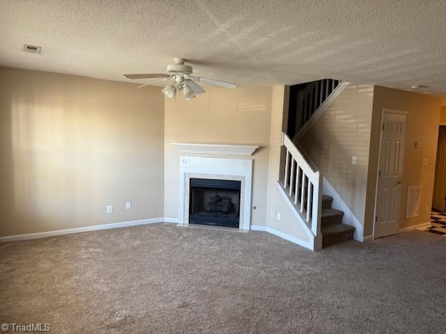 unfurnished living room with ceiling fan, carpet floors, and a textured ceiling