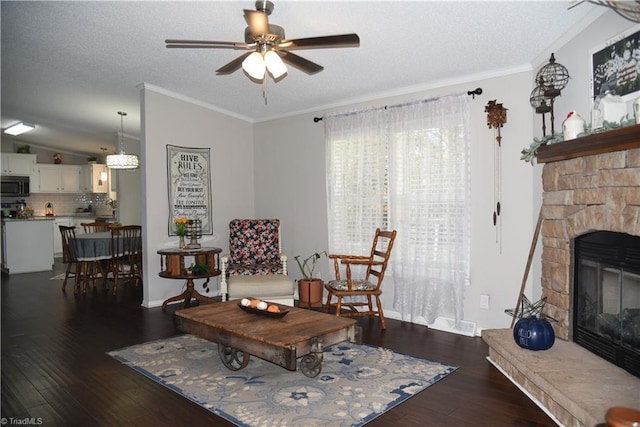 621 Southern Rd, King, NC 27021 - living area featuring ceiling fan, a textured ceiling, dark wood-style flooring, a stone fireplace, and crown molding