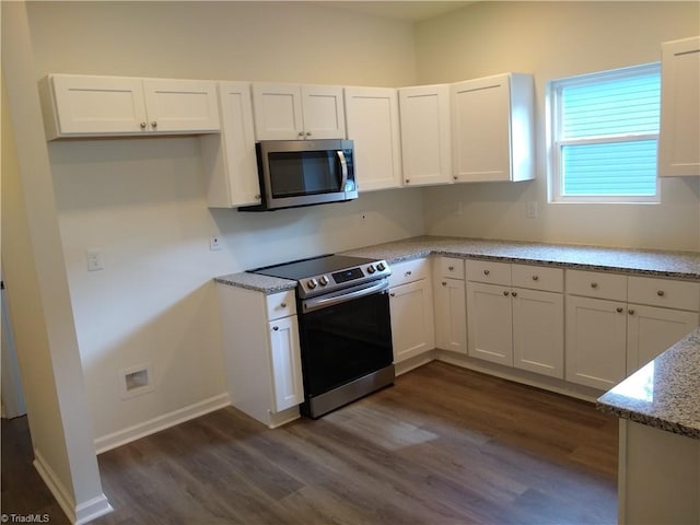 kitchen with white cabinets, stainless steel appliances, light stone counters, and dark wood-type flooring