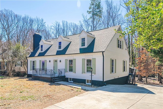 cape cod house featuring a shingled roof, concrete driveway, and covered porch