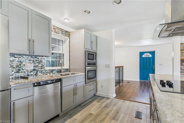 3640 Wyandotte Ave, Winston-Salem, NC 27127 - kitchen featuring stainless steel appliances, ventilation hood, tasteful backsplash, light wood-type flooring, and light stone counters