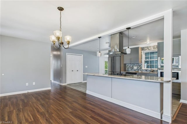 3640 Wyandotte Ave, Winston-Salem, NC 27127 - kitchen featuring appliances with stainless steel finishes, island exhaust hood, dark wood-type flooring, decorative backsplash, and a chandelier