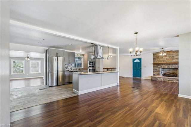 3640 Wyandotte Ave, Winston-Salem, NC 27127 - kitchen with stainless steel appliances, wall chimney range hood, a ceiling fan, gray cabinetry, and open floor plan