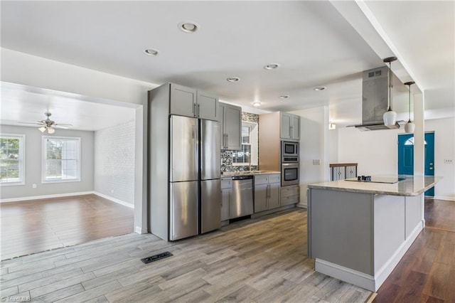 3640 Wyandotte Ave, Winston-Salem, NC 27127 - kitchen with stainless steel appliances, wall chimney range hood, gray cabinets, wood finished floors, and ceiling fan