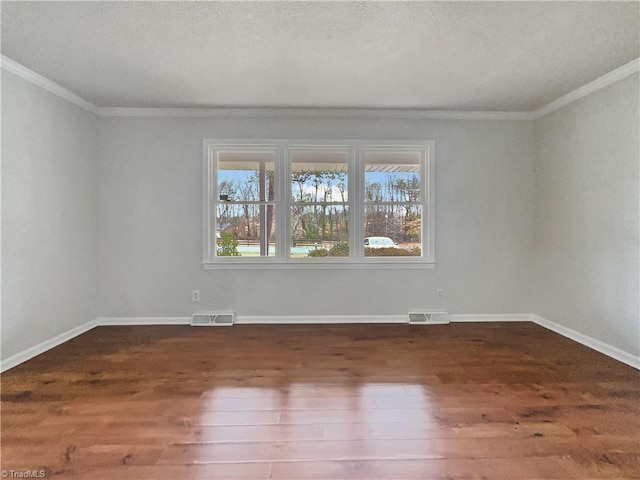 spare room featuring dark wood-style flooring, plenty of natural light, and visible vents