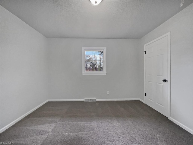 empty room with a textured ceiling, carpet, visible vents, and baseboards