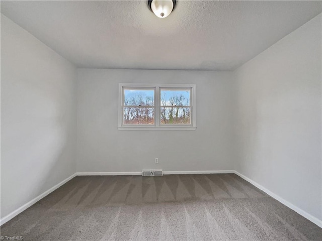 carpeted spare room with visible vents, baseboards, and a textured ceiling