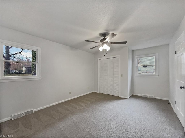 unfurnished bedroom with carpet, multiple windows, and visible vents