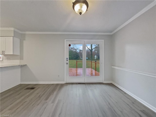 unfurnished dining area with light wood-style flooring, visible vents, baseboards, and ornamental molding