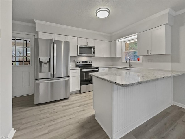 kitchen with appliances with stainless steel finishes, white cabinetry, a peninsula, and light stone countertops