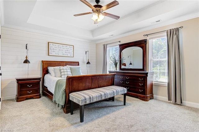 bedroom with light carpet, multiple windows, a tray ceiling, and ceiling fan